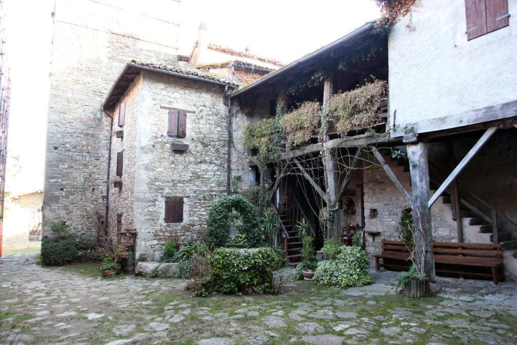 Cortile della pieve di Roffeno, scala esterna coperta con stilate in legno.